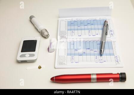 Diabetes, left blood glucose meter, test strip, lancing device, insulin pen, blood glucose diary, Germany Stock Photo