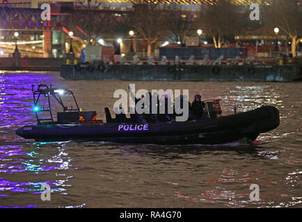 A Metropolitan Police boat patrols the River Thames as revellers wait for the start of fireworks on London's Embankment for the New Year celebrations. Stock Photo