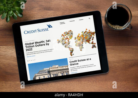 The website of Credit Suisse bank is seen on an iPad tablet, on a wooden table along with an espresso coffee and a house plant (Editorial use only). Stock Photo