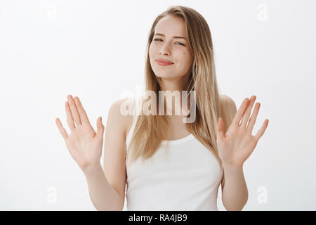 Not really into it. Portrait of woman refusing offer in polite manner smiling friendly wirh sorry look as waving hands in rejection gesture being ininterested and not in mood over gray background Stock Photo