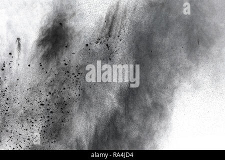 Black powder explosion against white background.The particles of charcoal splatted on white background. Closeup of black dust particles explode isolat