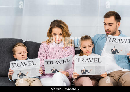 family sitting on sofa and reading travel newspapers in apartment Stock Photo