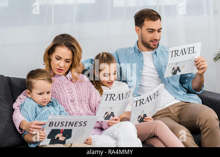 family sitting on sofa and reading travel and business newspapers in living room Stock Photo