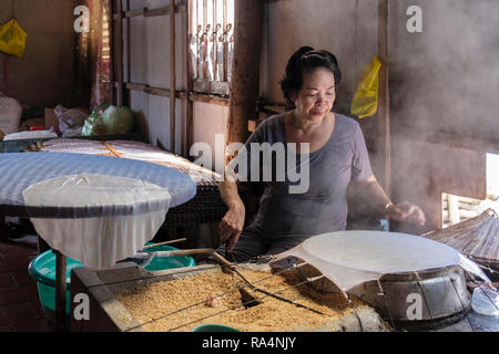 Vietnamese woman using rice grains to make rice paper wraps in a demonstration workshop. Cai Be, Tiền Giang Province, Mekong Delta, Vietnam, Asia Stock Photo