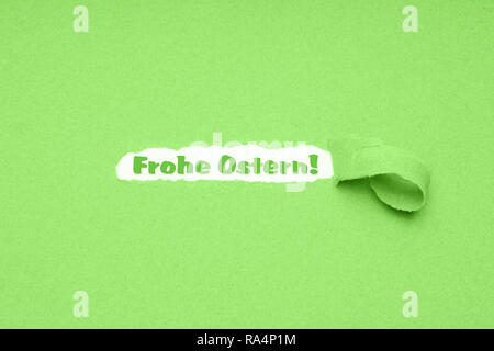 Frohe Ostern is German for Happy Easter - hole torn in green paper background to reveal easter greeting Stock Photo