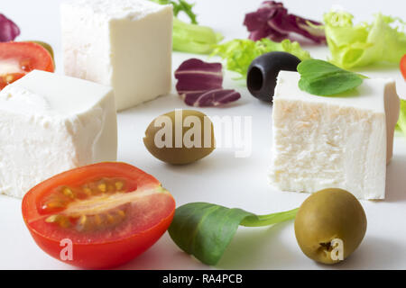 Greek salad, white Greek cheese, green and black olives, lettuce leaves, halfs of cherry tomato. White background. variations of salad leaves and feta Stock Photo