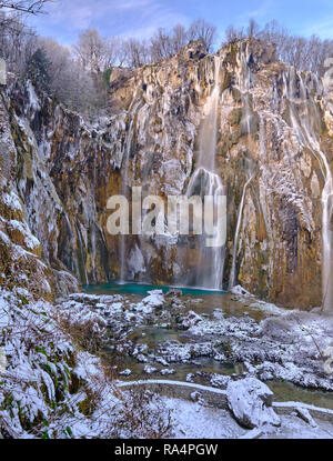 Portrait of Frozen big waterfall, covered in snow and ice falling into green pool of water. bottom of horseshoe cliffs . Scene in Plitvice NP Stock Photo