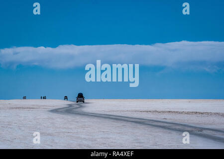 Vehicles driving through Salar de Uyuni salt flats along a winding track, Bolivia, South America Stock Photo