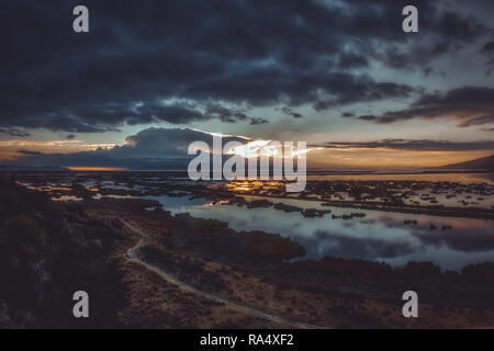 Colors of sunrise over Lake Titicaca in Peru, with dark morning clouds reflecting in calm water surface Stock Photo
