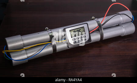 Pipe bomb with an lcd clock timer to trigger detonation, on wooden table Stock Photo