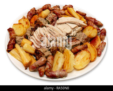 Roast turkey dinner serving platter with potatoes, parsnips, pigs in blankets and stuffing on an isolated white background Stock Photo