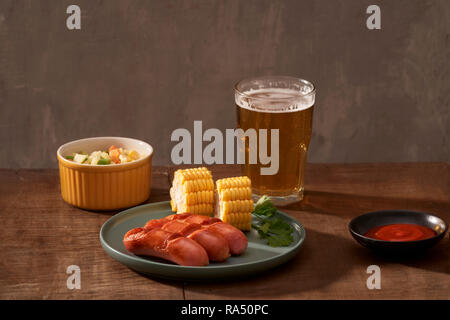 Home grilled sausages on a dark plate, a meat dish on a dark wooden background, hot sausages with spices and salt in a home kitchen, copy space, rusti Stock Photo