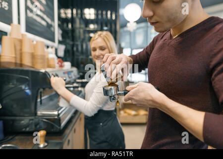 Barista man and woman making coffee, couple of young people working in coffee shop. Stock Photo