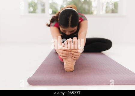 Young attractive yogi woman practicing yoga concept, sitting in Janu Sirsasana exercise, Head to Knee Forward Bend pose, working out wearing black spo Stock Photo