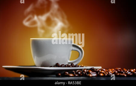 White cup of hot coffee with smoke and coffee beans on orange background Stock Photo