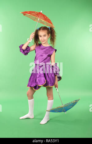 Pretty girl posing for the camera, in a violet short dress. Isolated on green. Stock Photo