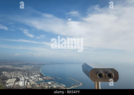 Metal grey coin operated telescope isolated at beautiful summer panoramic view at cityscape, blue sky and sea water. Turkey, Antalya city. Stock Photo