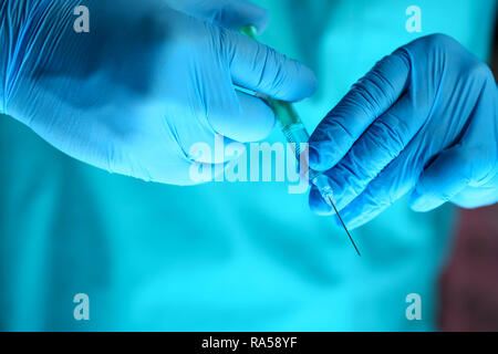 Physician injector arms in sterile uniform holding syringe Stock Photo