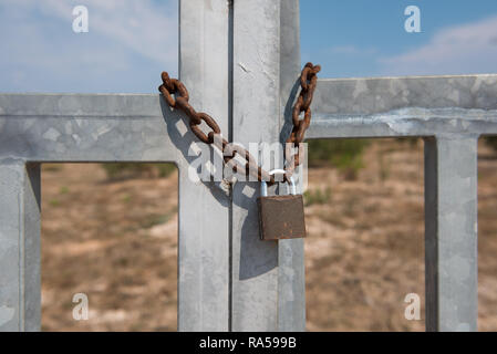 Old rusty metal lock hanging on a rusty metal chain. Closed metal doors Stock Photo