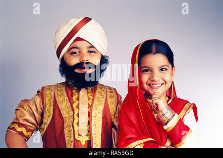 YOUNG BOY AND GIRL DRESSED AS A SIKH COUPLE IN TRADITIONAL COSTUME. BOY IS WEARING A FALSE BEARD Stock Photo