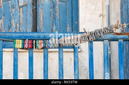 Many old clothespins are strung together on a line outside on a blue wooden balcony parapet in a Greek village Stock Photo