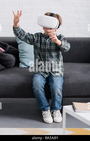 child sitting on couch and using virtual reality headset at home Stock Photo