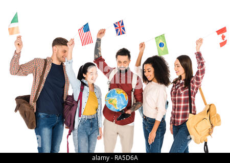 multiethnic group of people standing with backpacks and looking at globe while holding flags of different countries above heads isolated on white Stock Photo