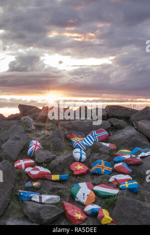 Different national flags painted on stones outdoors in Borgarfjordur in Iceland during beautiful sunset. Travel and national concept.
