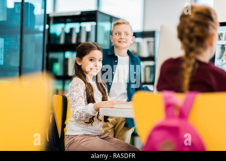 cute smiling schoolchildren studying with desktop computers in library Stock Photo