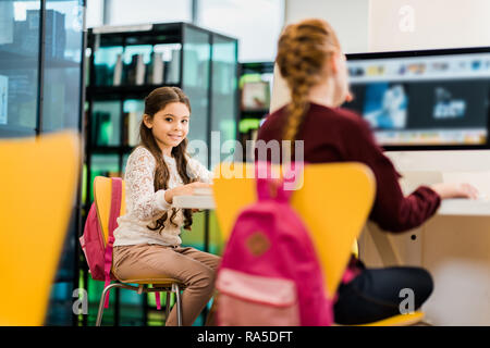 adorable schoolgirls using desktop computers in library Stock Photo