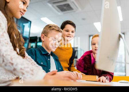 adorable smiling schoolkids using desktop computer in library Stock Photo