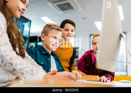 adorable smiling schoolchildren using desktop computer in library Stock Photo