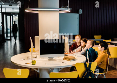 cute schoolchildren using desktop computers in modern library Stock Photo