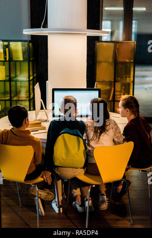 back view of four schoolchildren using computers in modern library Stock Photo