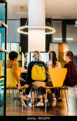 back view of four schoolkids using computers in modern library Stock Photo