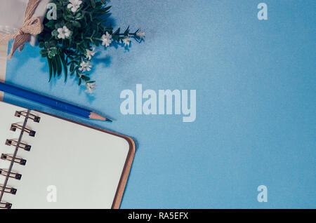 Top view with copy space, Blank notebook, pencil and tree in pots on a blue background Stock Photo