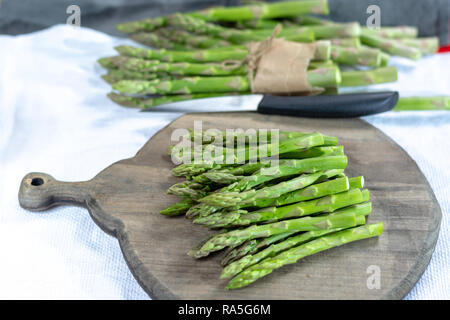 Fresh raw green asparagus vegetable on wooden plank close up Stock Photo
