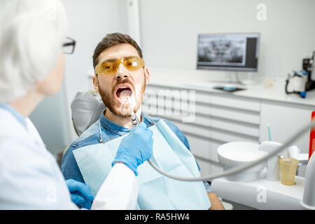 Handsome man during the medical examination with elderly woman dentist in the dental office Stock Photo