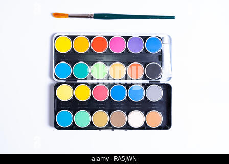 Flat lay of a colorful painting set and a paintbrush on white background with copy space Stock Photo