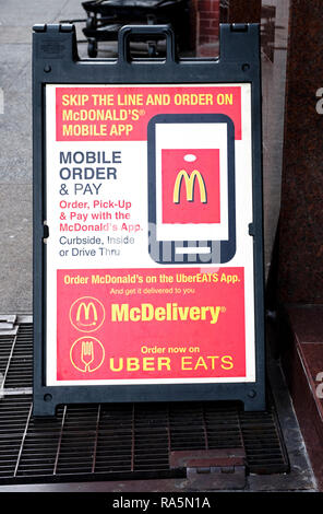 A sign outside a McDonald's in Greenwich Village promoting a new mobile app and the ability to order on McDelivery and Uber Eats. Stock Photo