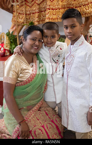 A posed portrait of a devout Hindu mother and her two sons in a temple in Jamaica, Queens, New York City. Stock Photo