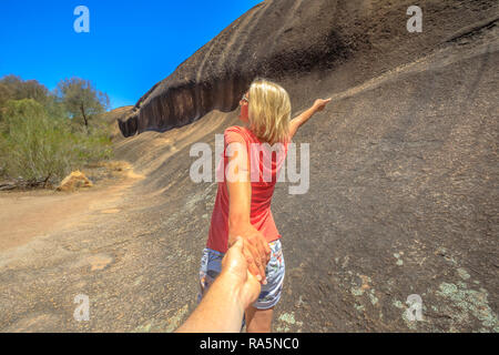 Follow me, woman holding hands at side of Wave Rock, along Wave Rock Walk Circuit in Hyden, Western Australia. Concept of the journey, holding man by hand. Hyden Wildlife Park in Australian outback.