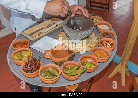 https://l450v.alamy.com/450v/ra5nf9/man-preparing-hand-made-salsa-in-a-mortar-and-pestle-with-many-small-terra-cotta-bowls-filled-with-ingredients-on-a-large-platter-in-oaxaca-mexico-ra5nf9.jpg