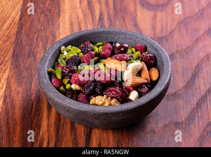 Various dried fruits and nuts in a ceramic bowl (walnut, cashew, almonds, pine nuts, hazelnuts) on a gray stone or slate background. The concept of a  Stock Photo