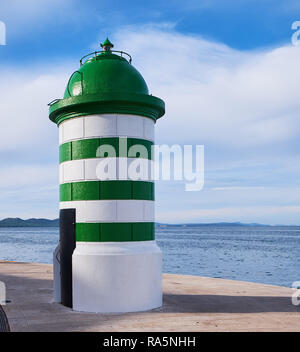 Simple striped green and white port beacon against a light cloudy background.  Guiding concept Stock Photo