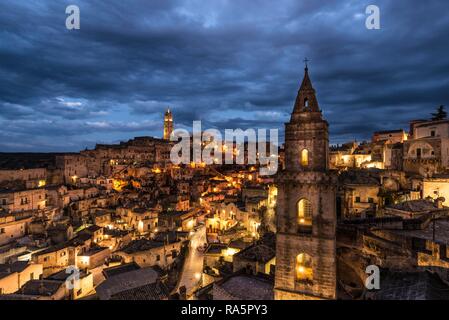 Church tower San Pietro Barisano in front of illuminated old town with cathedral, blue hour, Matera, Basilicata, Italy Stock Photo