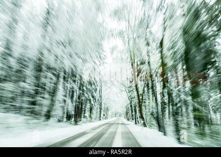 Snow-covered road in snow-covered forest, slippery road, Unterallgäu, Bavaria, Germany Stock Photo