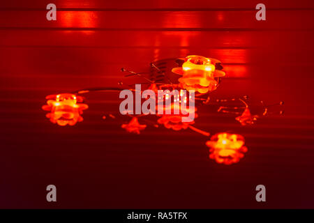 Modern ceiling lamp decorated with roses, shining red light in the dark, home interior background Stock Photo