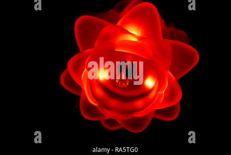 Macro closeup of a flower shaped lamp isolated in the dark, red led lights shining Stock Photo