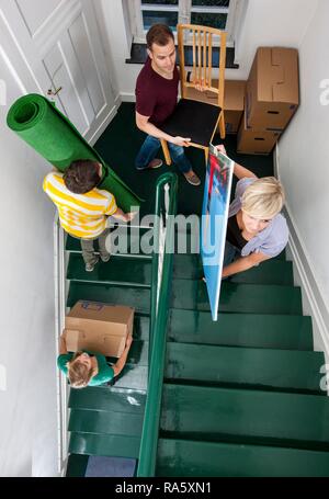 Private house move, friends helping, carrying boxes and furniture up the stairs Stock Photo